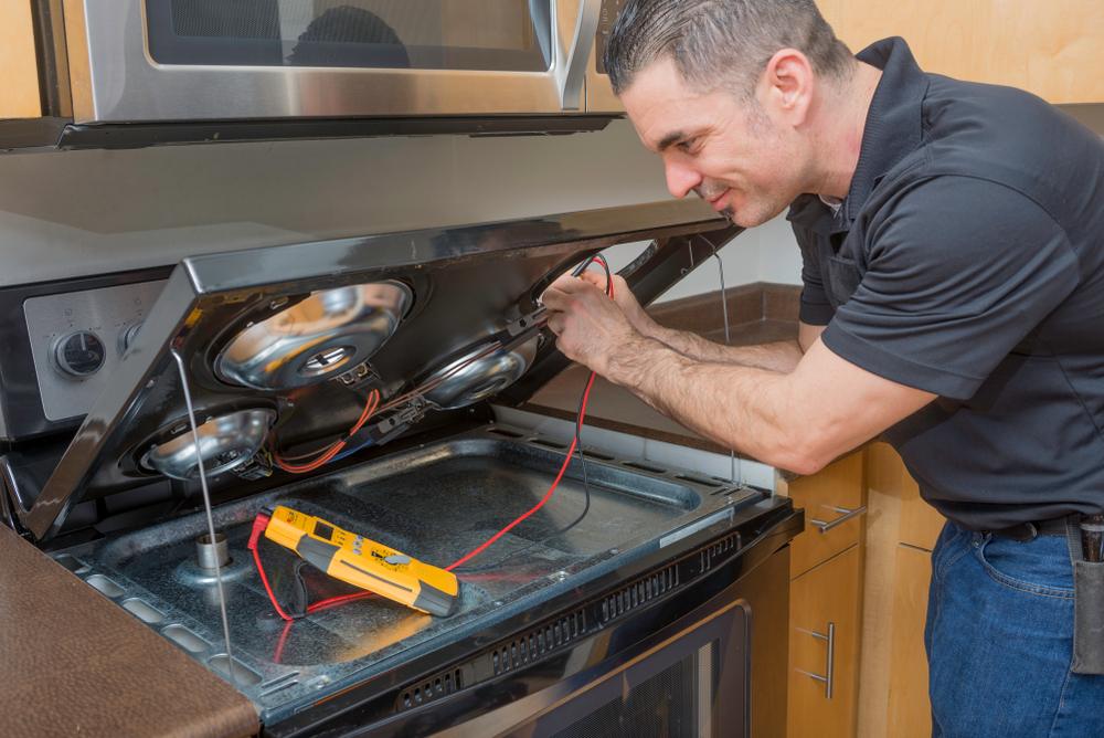 Unique Repair Services performs certified kitchen range repair in Des Plaines, IL. This image shows a factory-trained technician testing electrical components inside a kitchen range using professional diagnostic tools. Homeowners trust our same-day service and 90-day guarantee for safe, reliable range repairs that restore full performance.