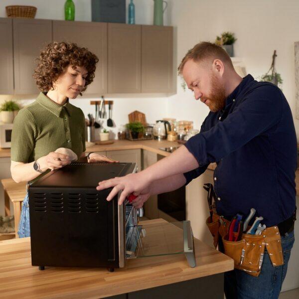 Technician repairing built-in microwave oven in a Naperville, IL kitchen.