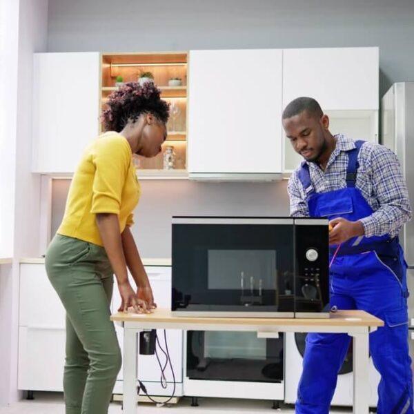 A microwave being repaired by a technician in an Indianapolis kitchen, with a homeowner observing—showcasing Unique Repair Services’ dependable appliance repair expertise in Indiana.