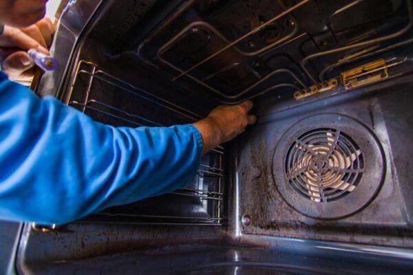 A technician repairing the inside of a dirty oven in Naperville, Illinois—highlighting the hands-on appliance repair services offered by Unique Repair Services.
