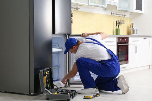 A refrigerator repair underway in an Indianapolis home, showing a technician inspecting a kitchen appliance—illustrating the reliable, same-day appliance repair services provided by Unique Repair Services.