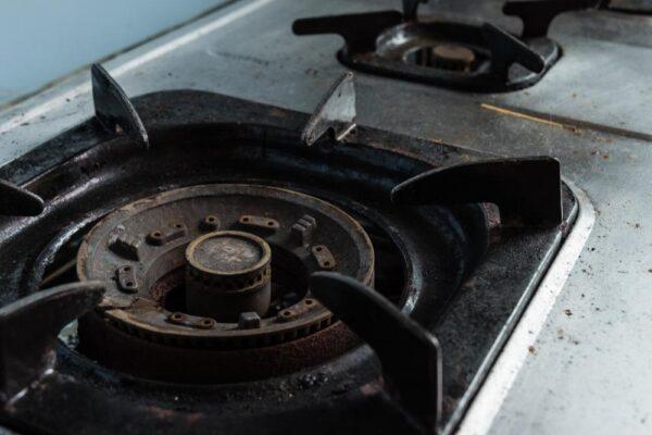 Samsung appliance repair showing a gas cooktop burner with buildup and wear, highlighting the need for professional cleaning and repair service.