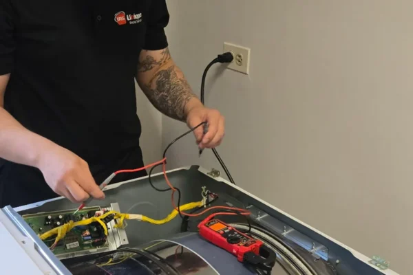Unique Repair technician testing a washer control board with a multimeter