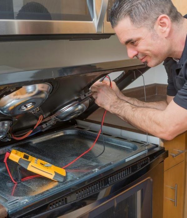 A technician repairs an electric range cooktop in an Indianapolis home, representing the hands-on appliance repair services provided by Unique Repair Services across Indiana.